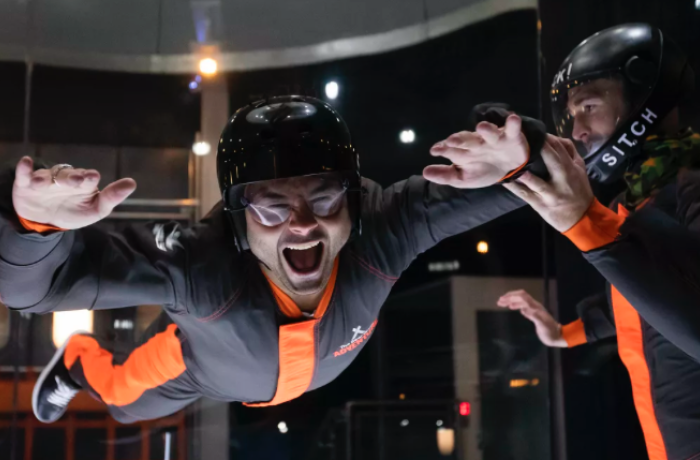 man wearing a black and orange suit doing an indoor skydiving experience