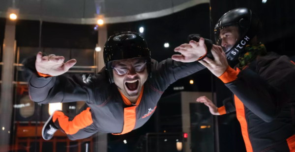 man wearing a black and orange suit doing an indoor skydiving experience
