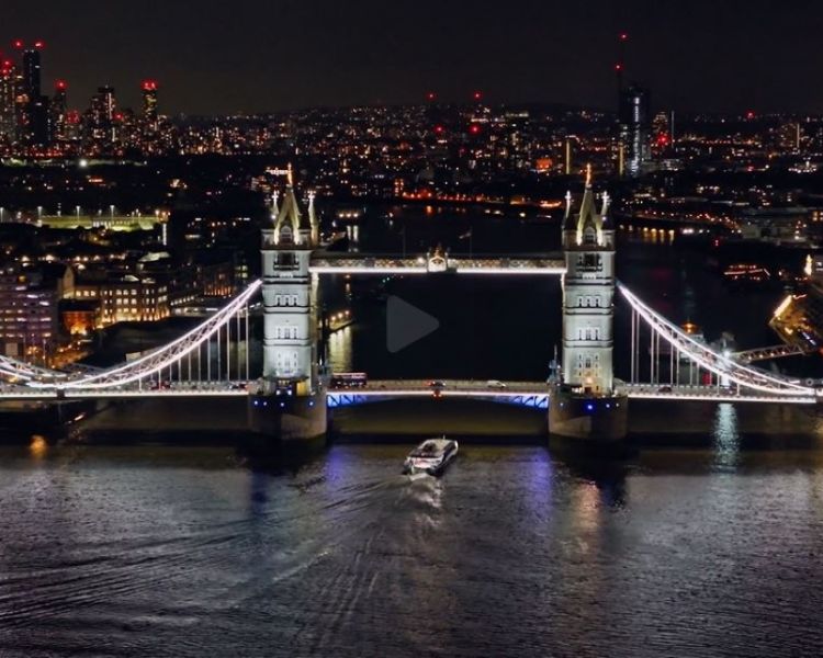 an uber boat going under tower bridge at night