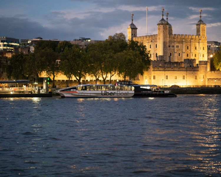 an uber boat going past the tower of london at night