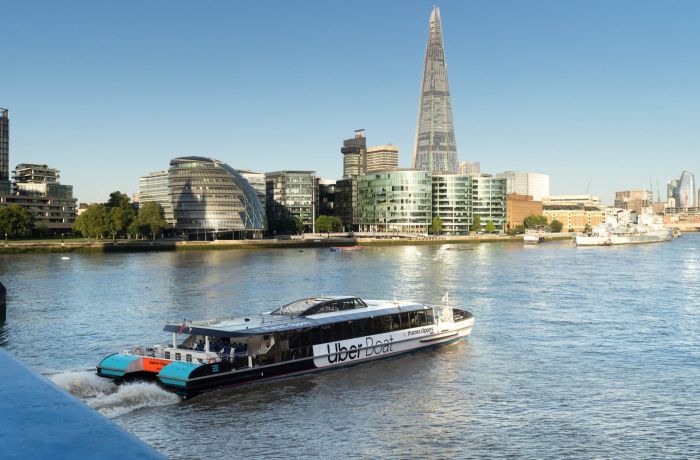 an uber boat passing by the shard on the river thames