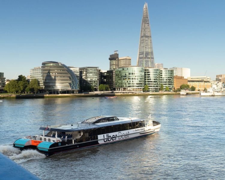 an uber boat passing by the shard on the river thames