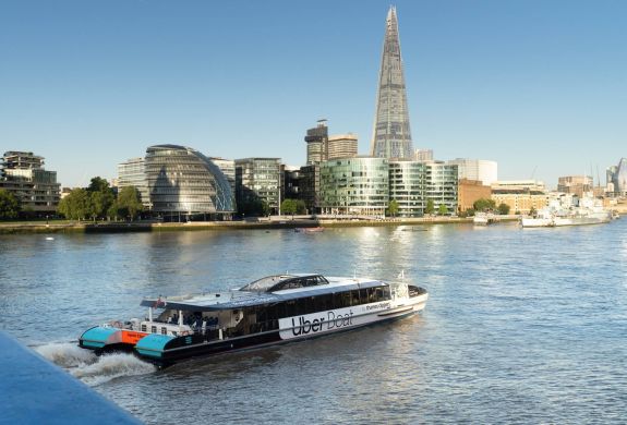 an uber boat passing by the shard on the river thames