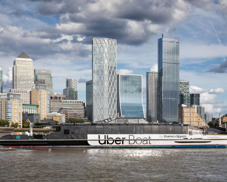 an uber boat passing canary wharf on the river thames