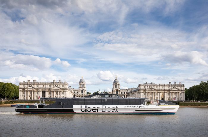 an uber boat passing the royal naval college on the river thames