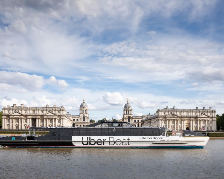 an uber boat passing the royal naval college on the river thames