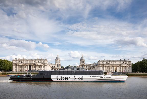 an uber boat passing the royal naval college on the river thames