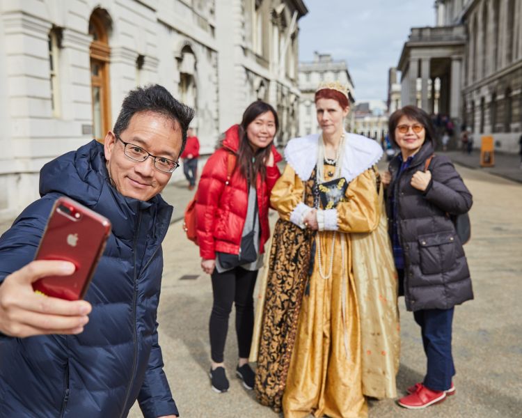 family taking photo with a costumed guide at old royal naval college in london