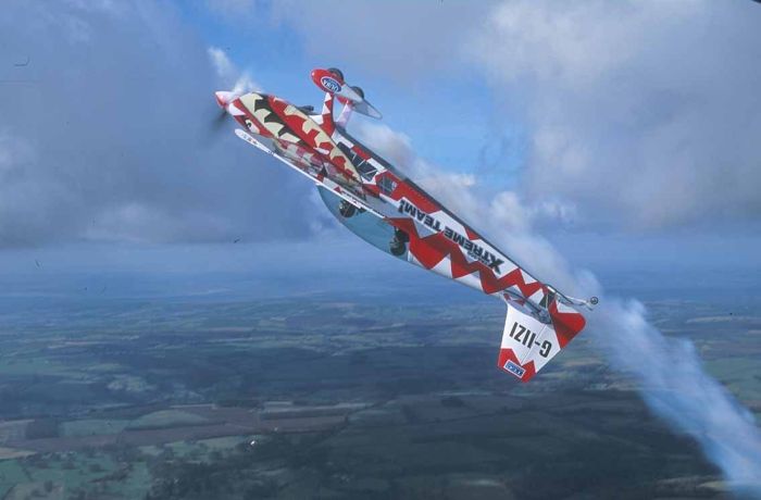 red and white aircraft upside down in the sky for an extreme aerobatic flying experience