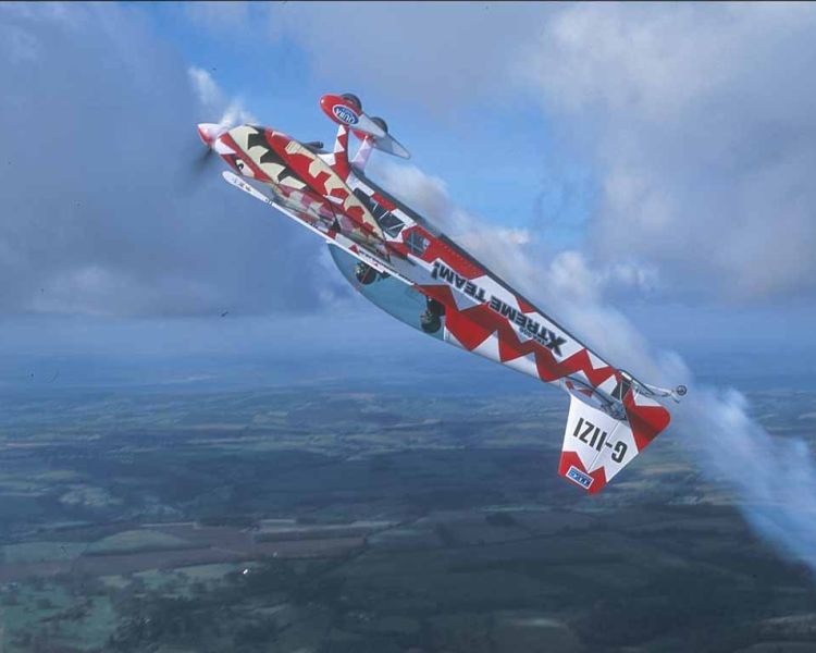 red and white aircraft upside down in the sky for an extreme aerobatic flying experience