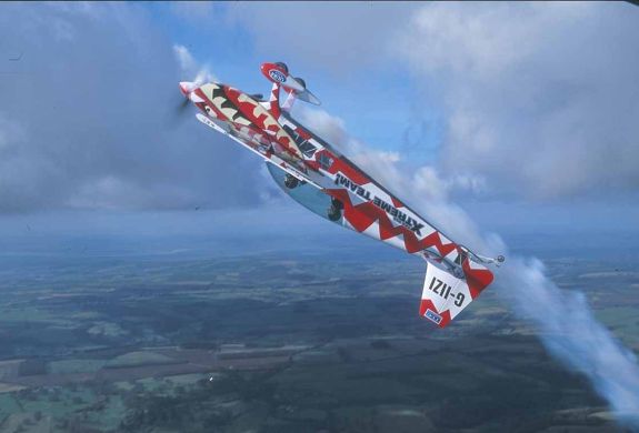 red and white aircraft upside down in the sky for an extreme aerobatic flying experience