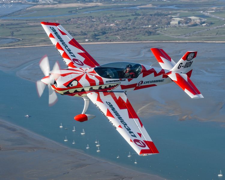 red and white plane flying over south east coastline for an aerobatic flying experience