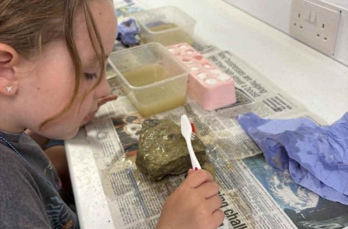 young girl cleaning a fossil on a young palaeontologist fossil experience at exotic zoo telford