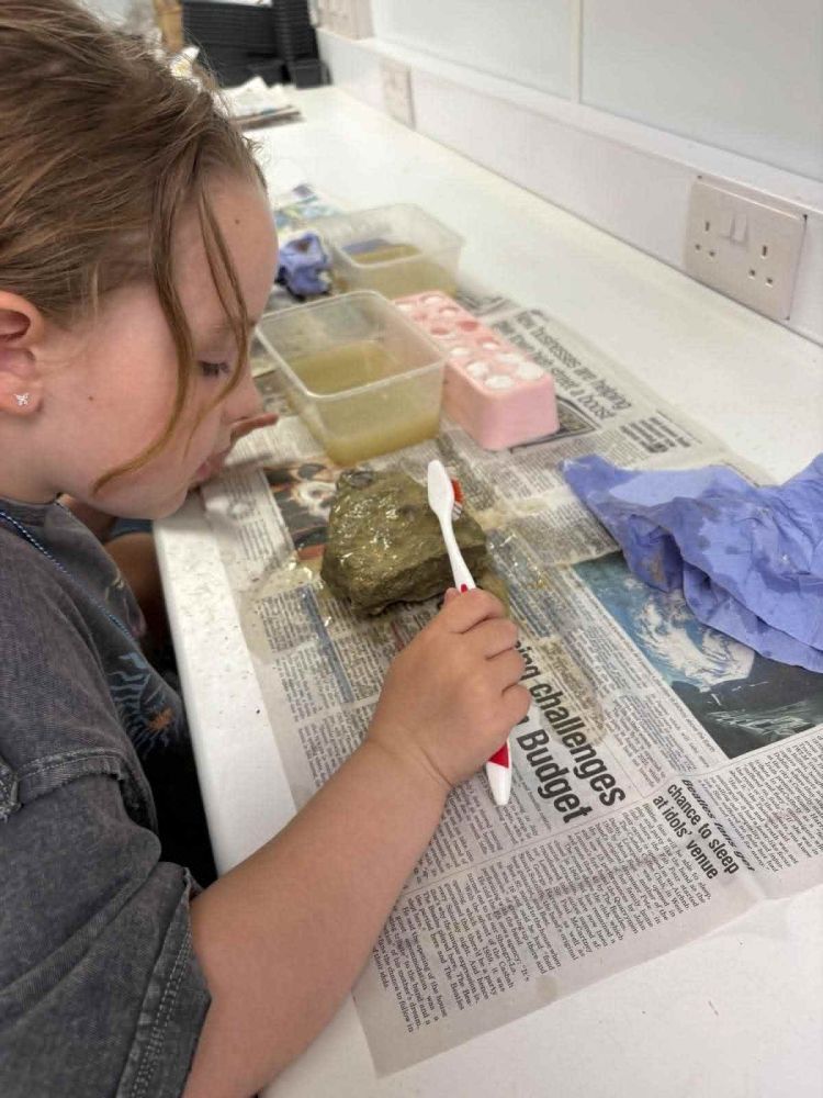 young girl cleaning a fossil on a young palaeontologist fossil experience at exotic zoo telford