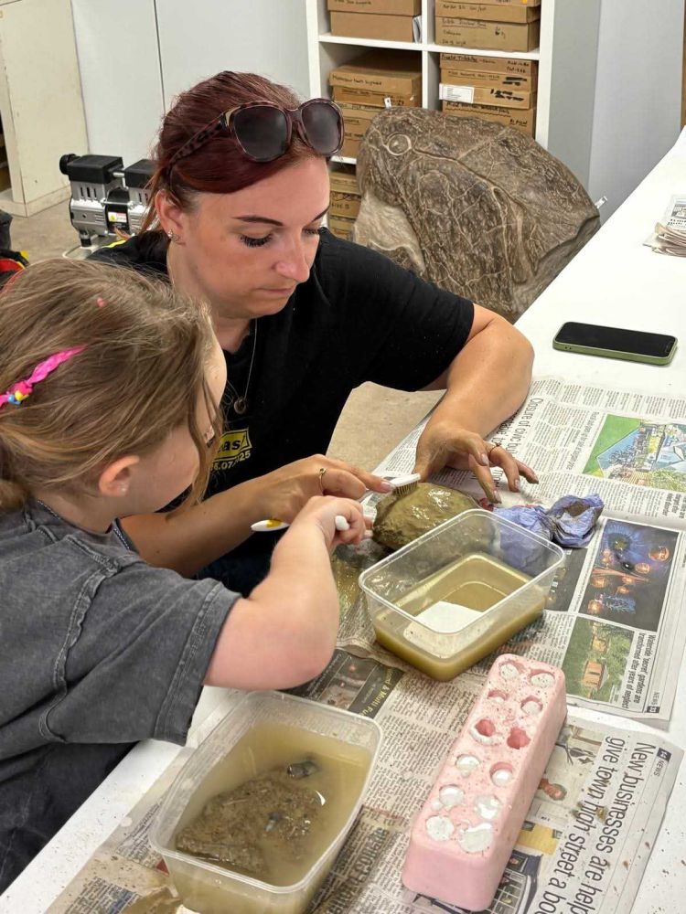 girl cleaning fossil with help on a young palaeontologist fossil experience at exotic zoo telford