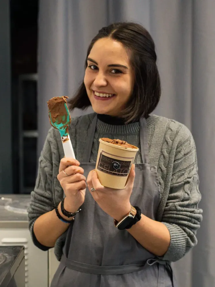 woman smiling and holding a tub of gelato on a learn how to make gelato workshop in london