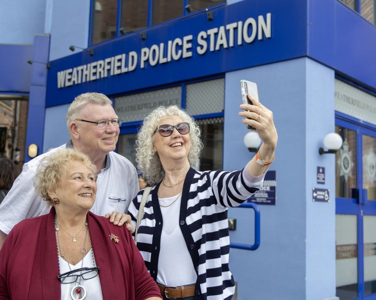 Fans pose for a selfie outside the police station