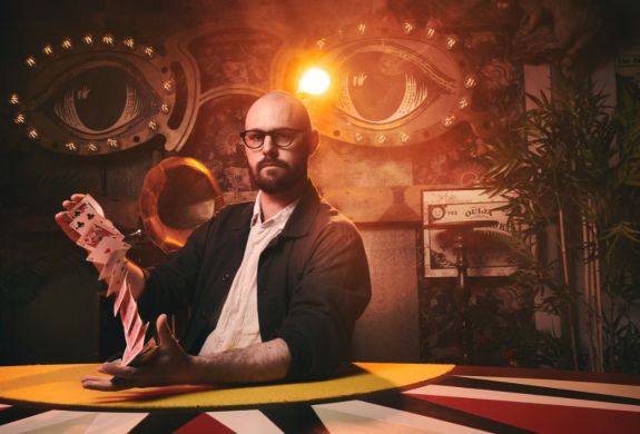Magician with deck of cards at the magicians table show london