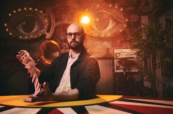 Magician with deck of cards at the magicians table show london