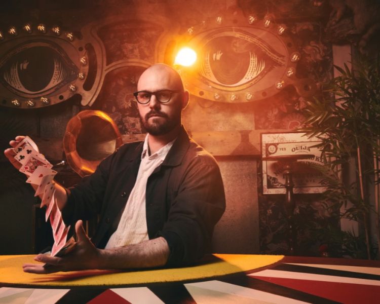Magician with deck of cards at the magicians table show london