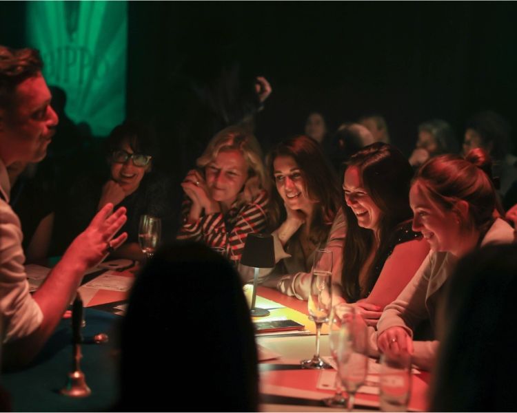 Guests laughing watching magician at the magicians table immersive show london