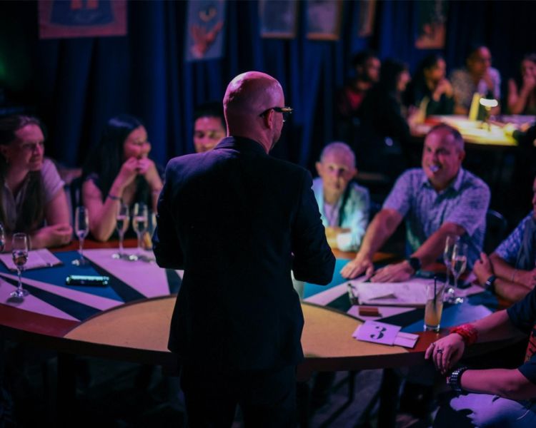 Guests watching magician at premium seating at the magicians table immersive show
