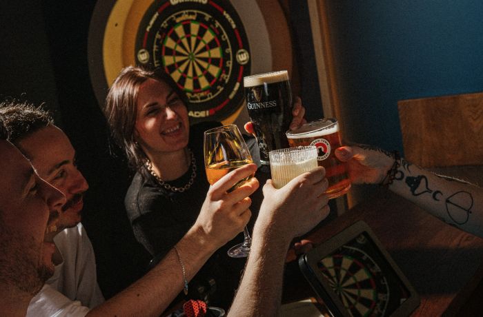 Four people with drinks playing darts at the lucky goat