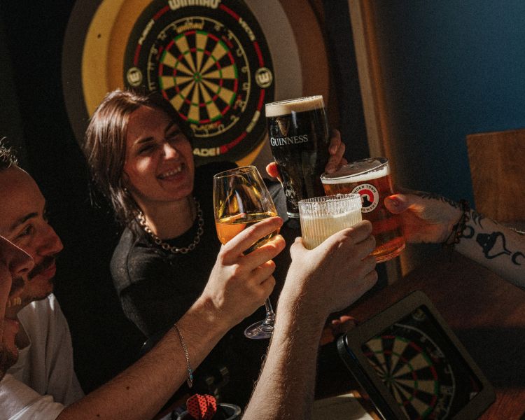 Four people with drinks playing darts at the lucky goat