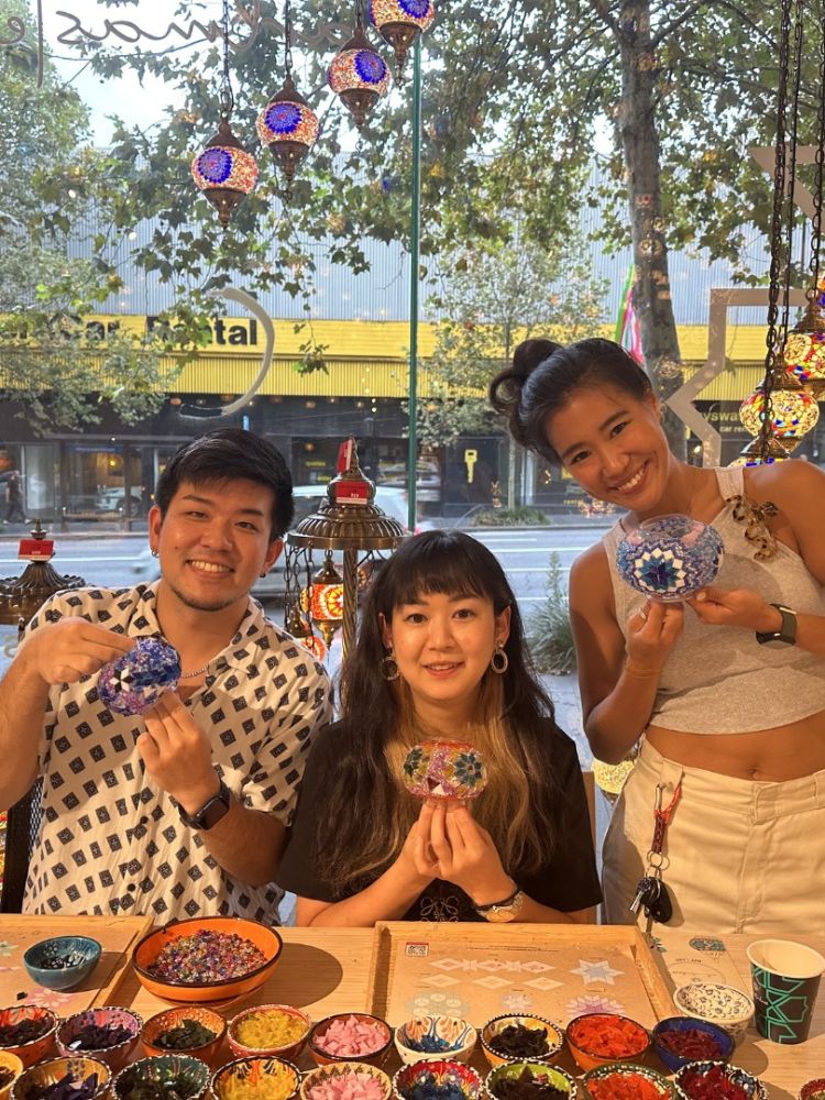 Three people holding their glass candle holders decorated with mosaic glass