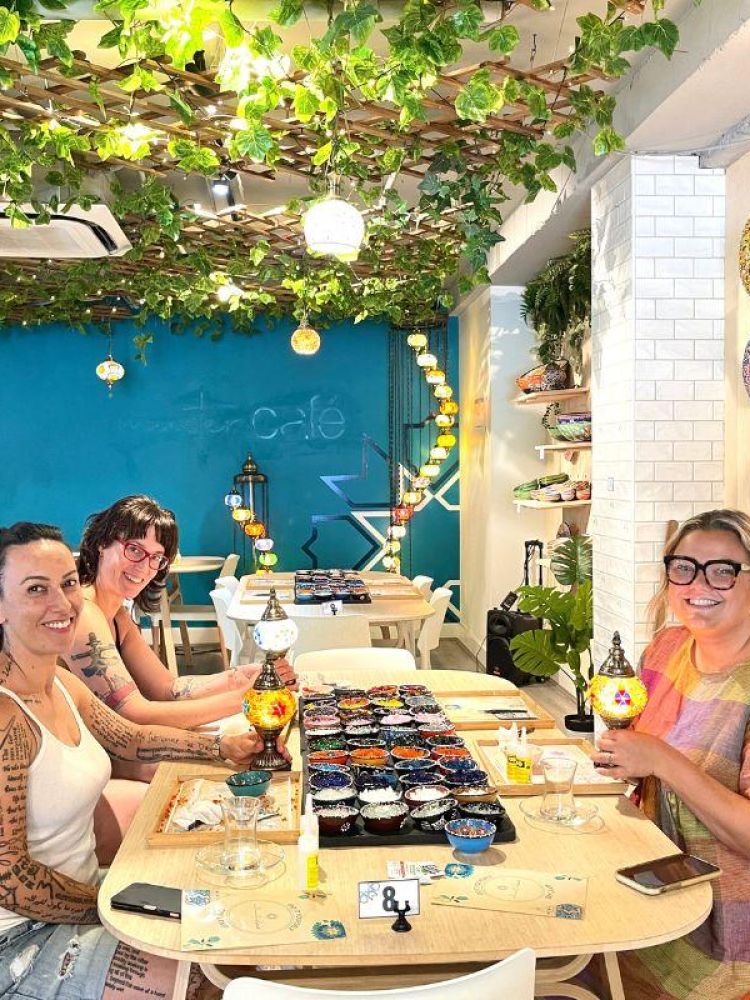 Three ladies decorating their turkish lamps with colourful mosaic glass