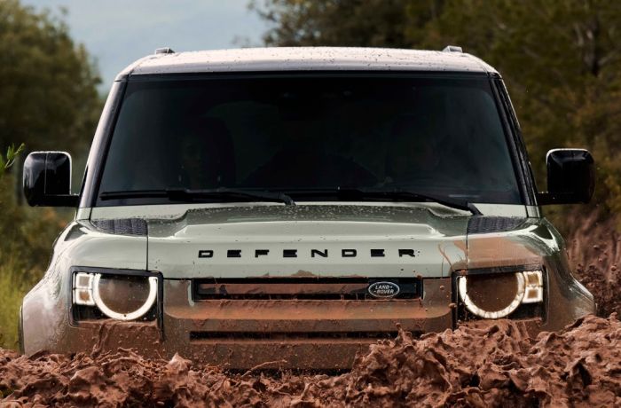 Land rover defender going through muddy water on driving experience