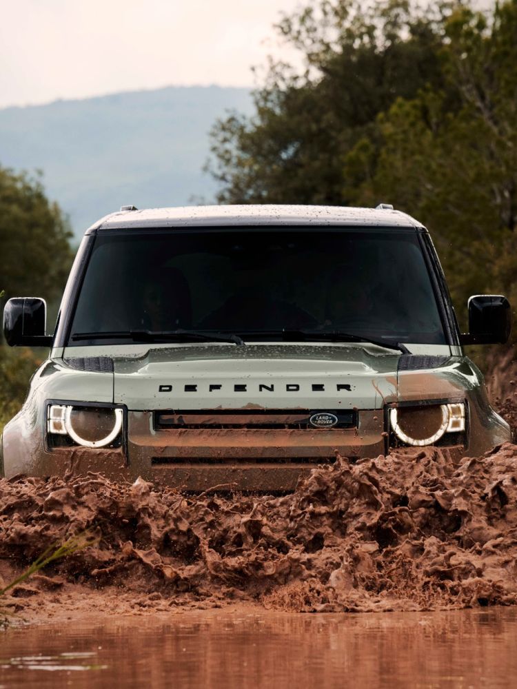 Land rover defender going through muddy water on driving experience