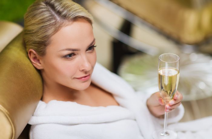 woman holding glass of champagne at spa