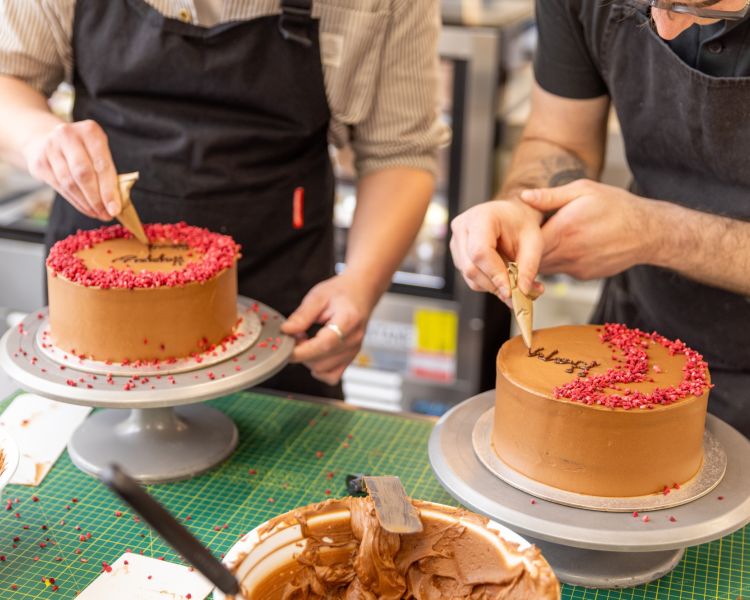 Two people decorating a red velvet cake at cake decorating class
