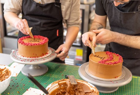 Two people decorating a red velvet cake at cake decorating class