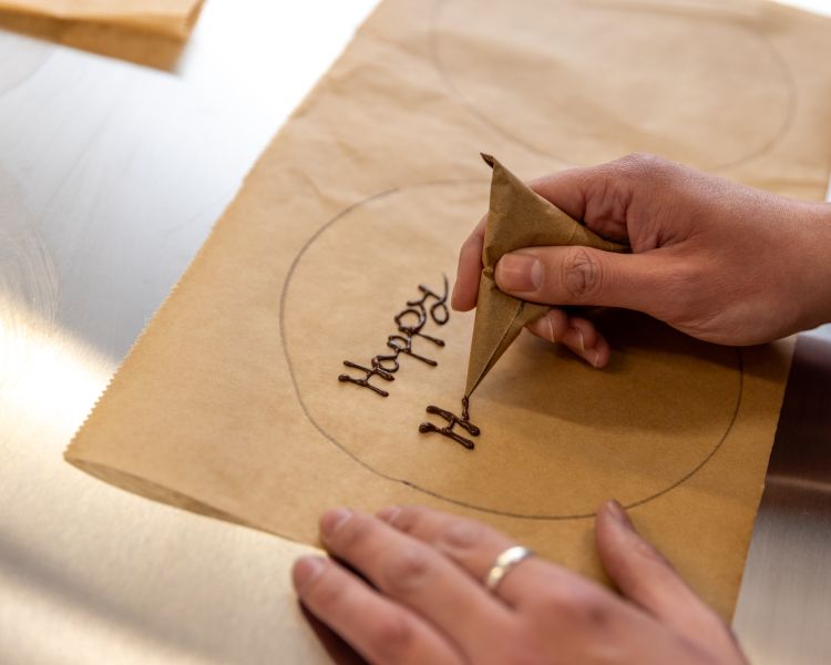 practicing writing with chocolate to decorate cake at cake decorating class in battersea