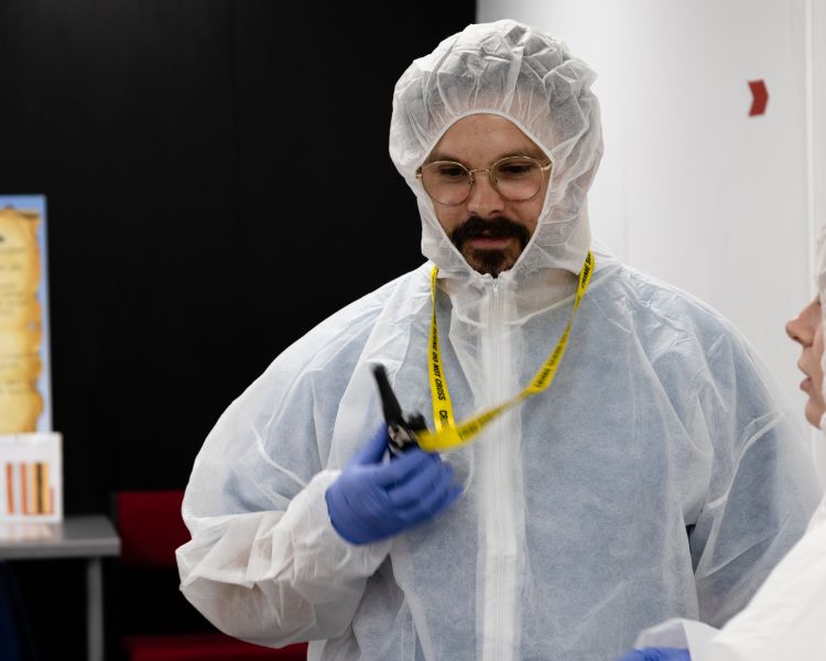A man in a white hasmat suit with a walkie talkie