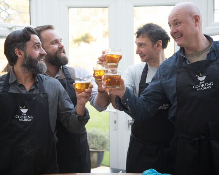 four men toasting glasses of beer on a cookery course experience day