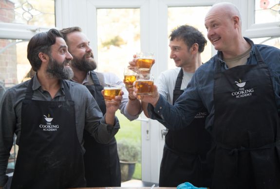 four men toasting glasses of beer on a cookery course experience day
