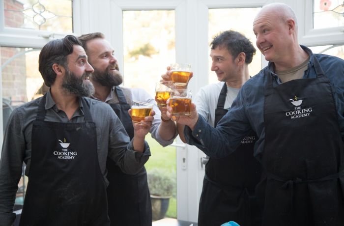 four men toasting glasses of beer on a cookery course experience day