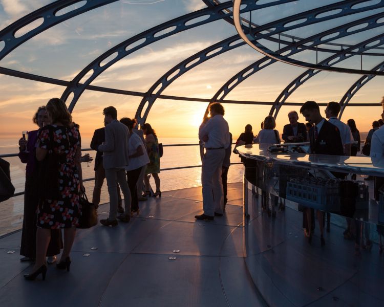 people enjoying the views out of the pod on the i360 in brighton as the sun is setting