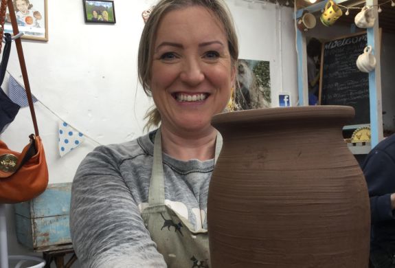 woman holding a clay vase she has made on pottery course experience day