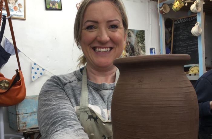 woman holding a clay vase she has made on pottery course experience day