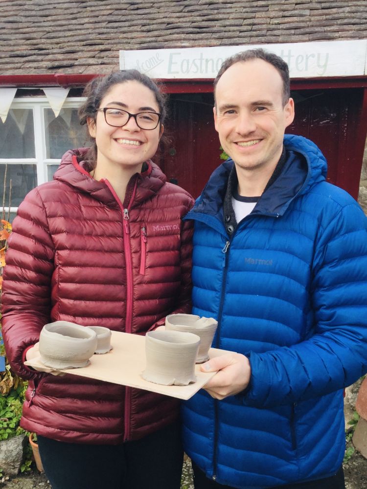 woman and man holding a board with their clay creations on it made on a pottery course experience day