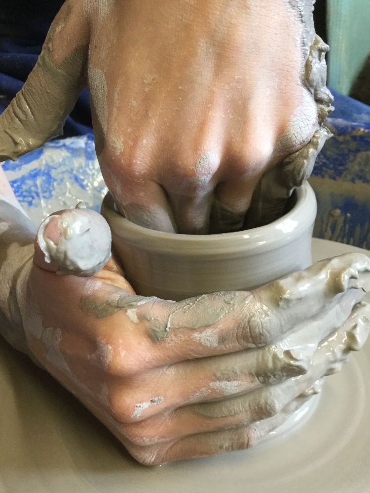 person making a clay pot on a potters wheel on a pottery course experience day