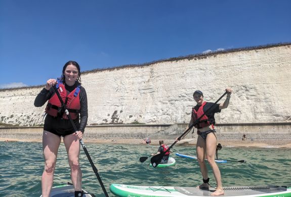 ladies on paddleboard experience off brighton coast