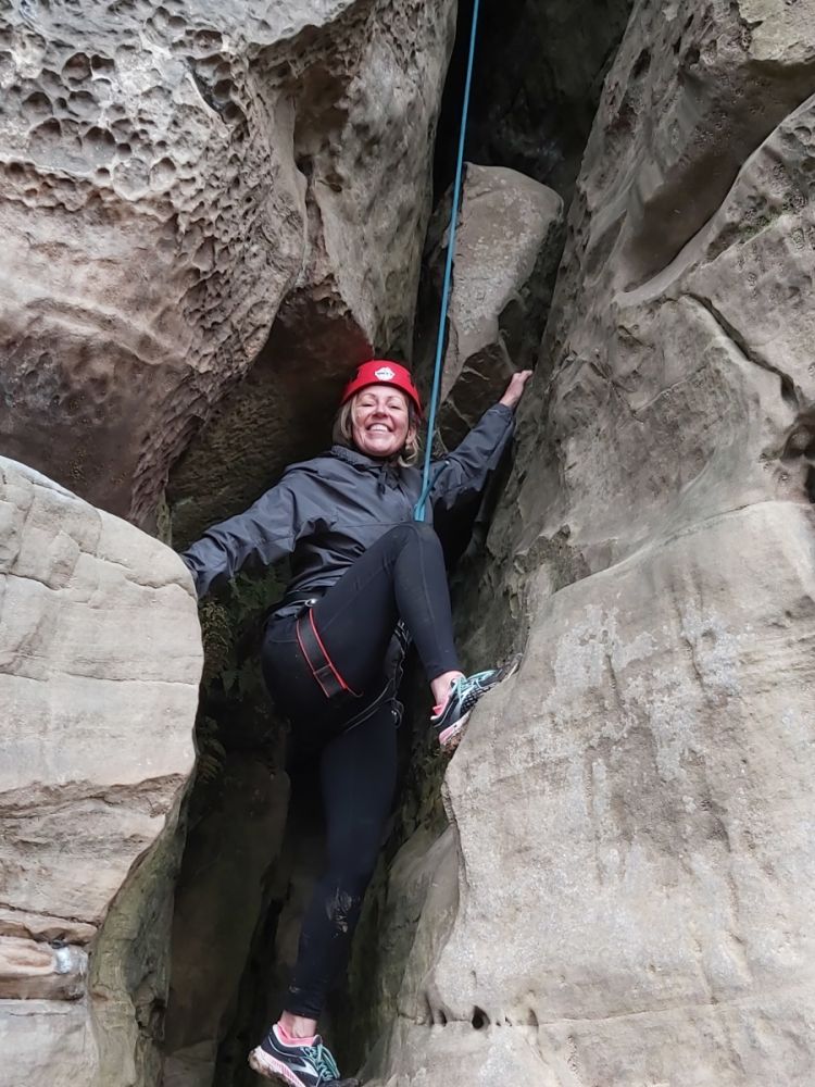woman standing between rocks on rock climbing experience in sussex and kent