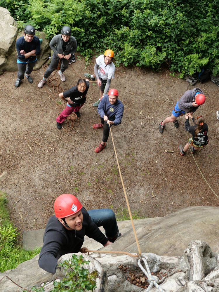 group watching man scaling rocks on rock climbing experience in sussex and kent