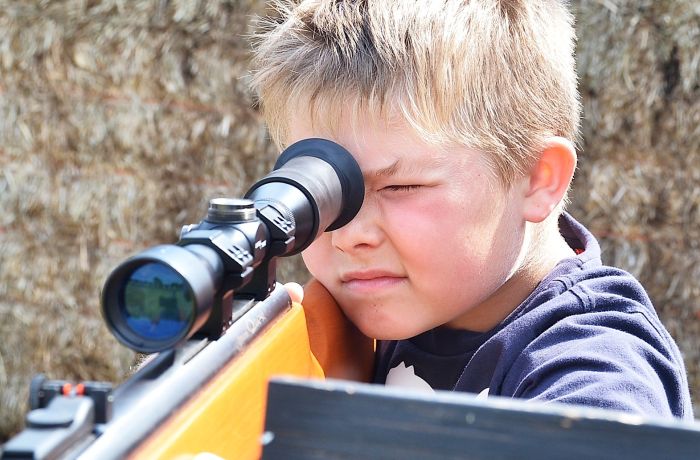 young boy aiming an air rifle on a spy camp experience day for kids