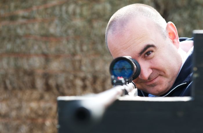 man aiming an air rifle while on a spy camp experience day for adults